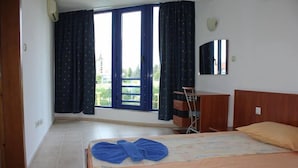 A hotel room with a bed, a desk, and a window with curtains. - Sveti Vlas Hotel (Sveti Vlas)