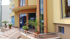 A building with a curved entrance, potted plants, and a sign indicating a business center. - Sveti Vlas Hotel (Sveti Vlas)