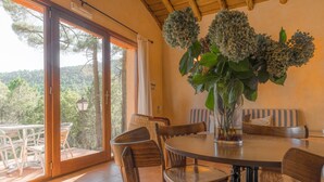 A dining area with a round table, chairs, and a large window with a view of trees.