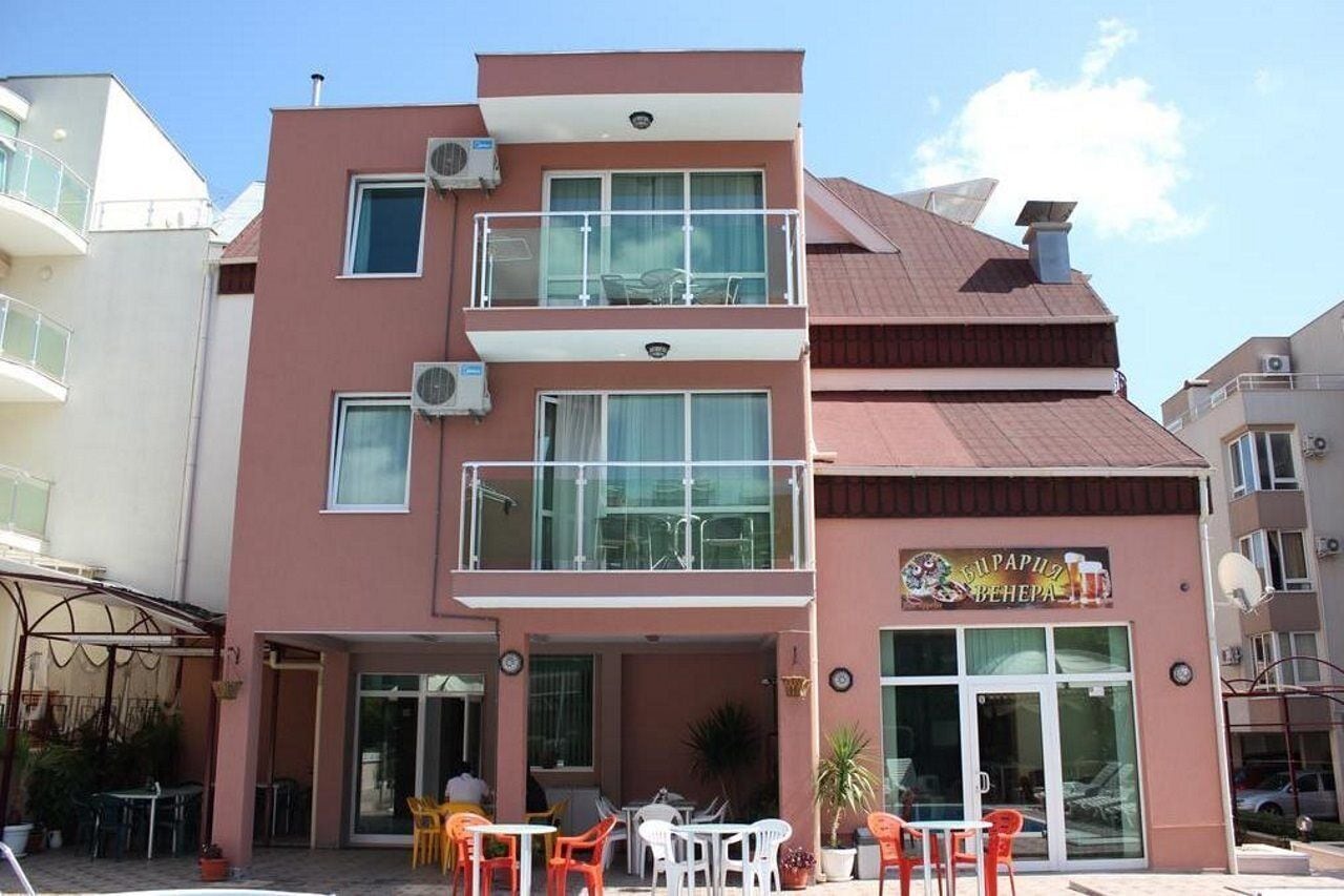 A two-story building with a balcony, outdoor seating, and a sign for a restaurant.