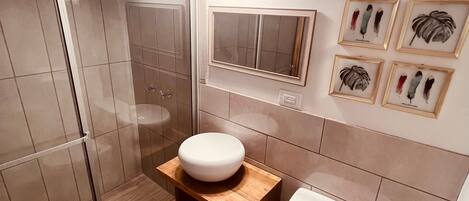 Une salle de bain moderne avec une douche à parois de verre, des toilettes blanches et un meuble-lavabo en bois avec un évier.