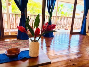 A wooden floor with a woven basket containing red flowers and a wooden bowl. - Casa Le Parc (Bocas del Toro)