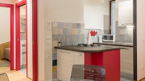 A modern kitchen with a red accent wall, a microwave, and a sink. - Casa Sottoriva (Verona)