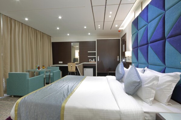 A hotel room with a large bed, a desk, and a chair.