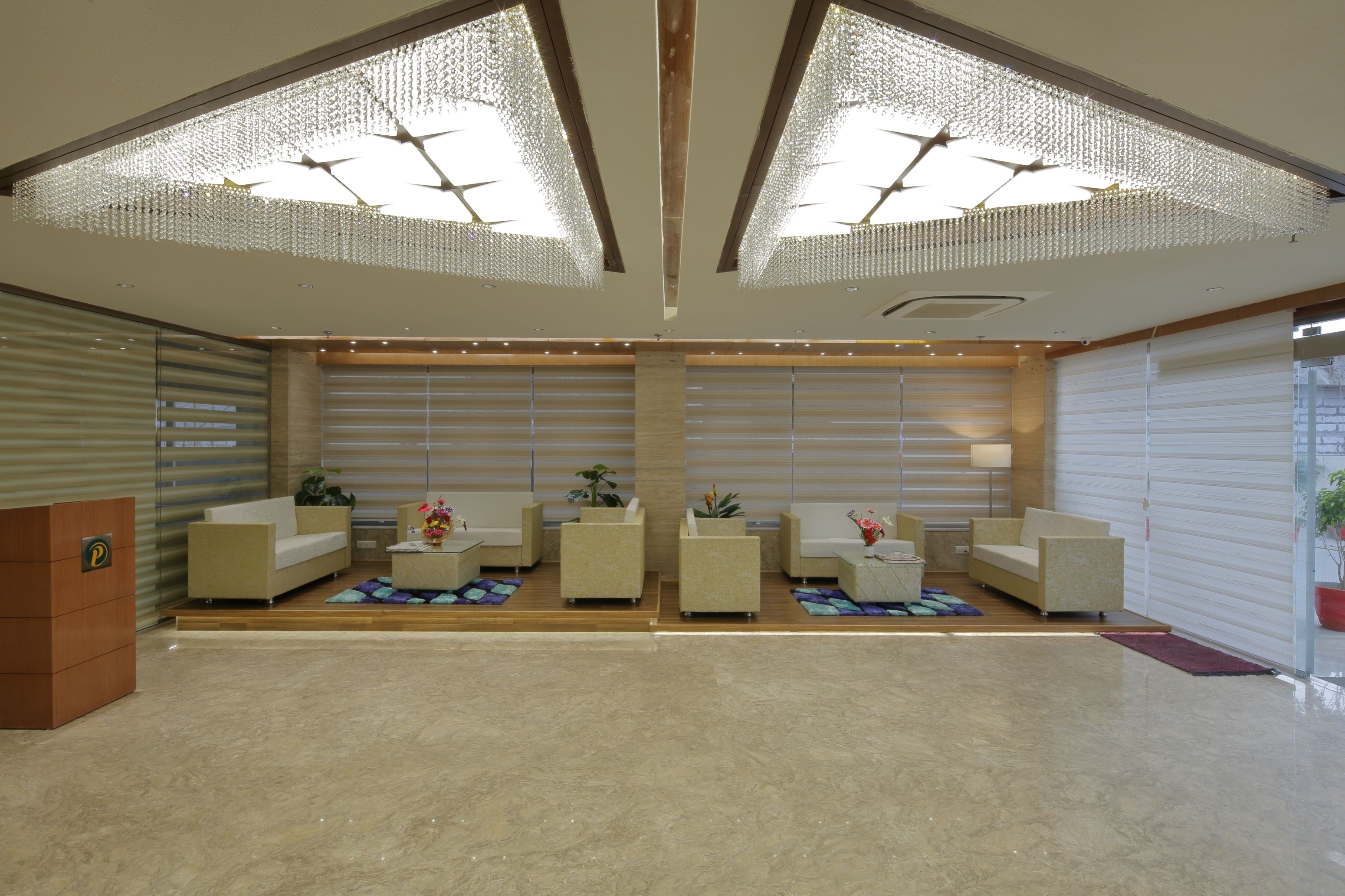 A modern lobby with a reception desk, seating area, and large windows.