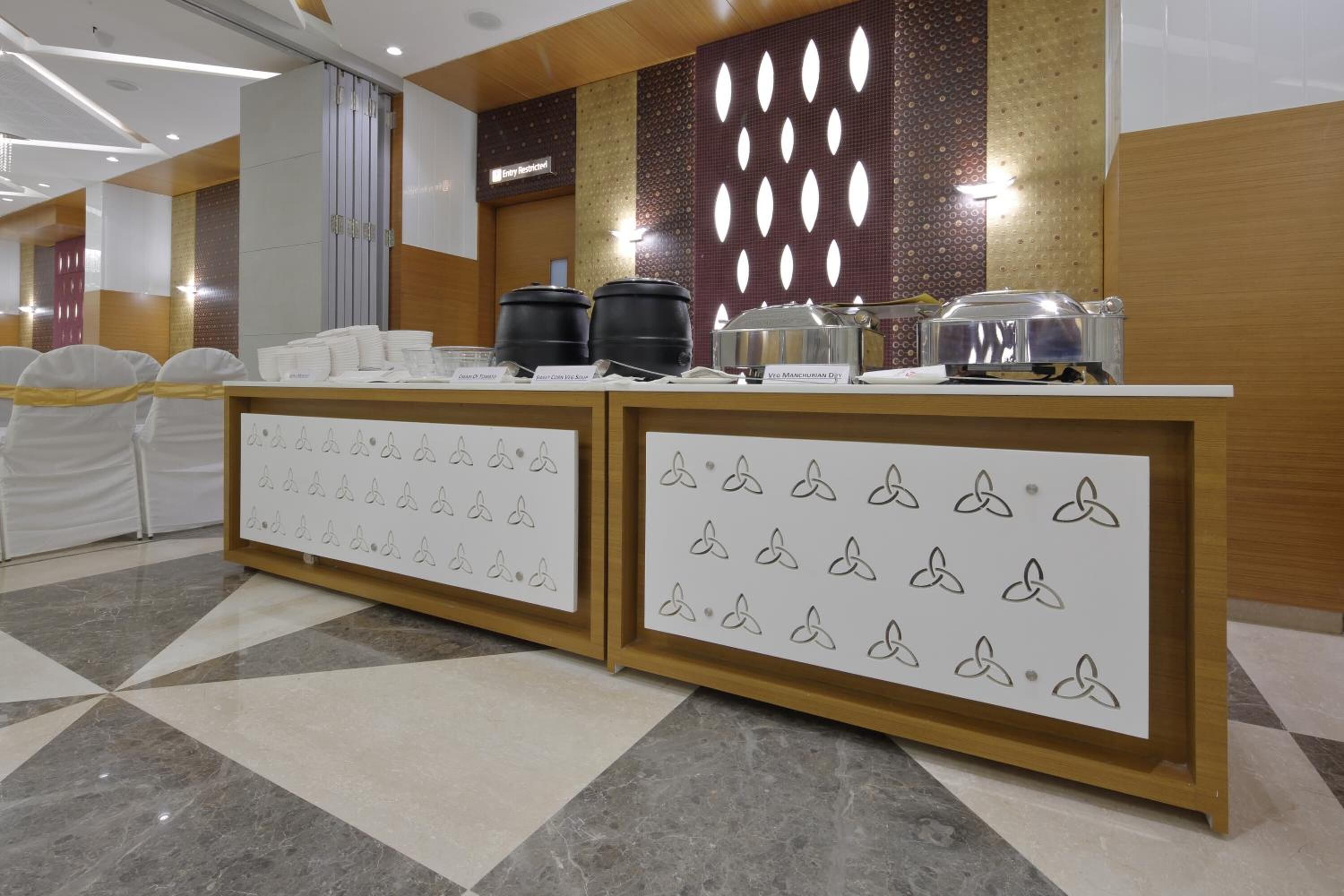 A reception area with a counter displaying food items and a decorative wall with a geometric pattern.