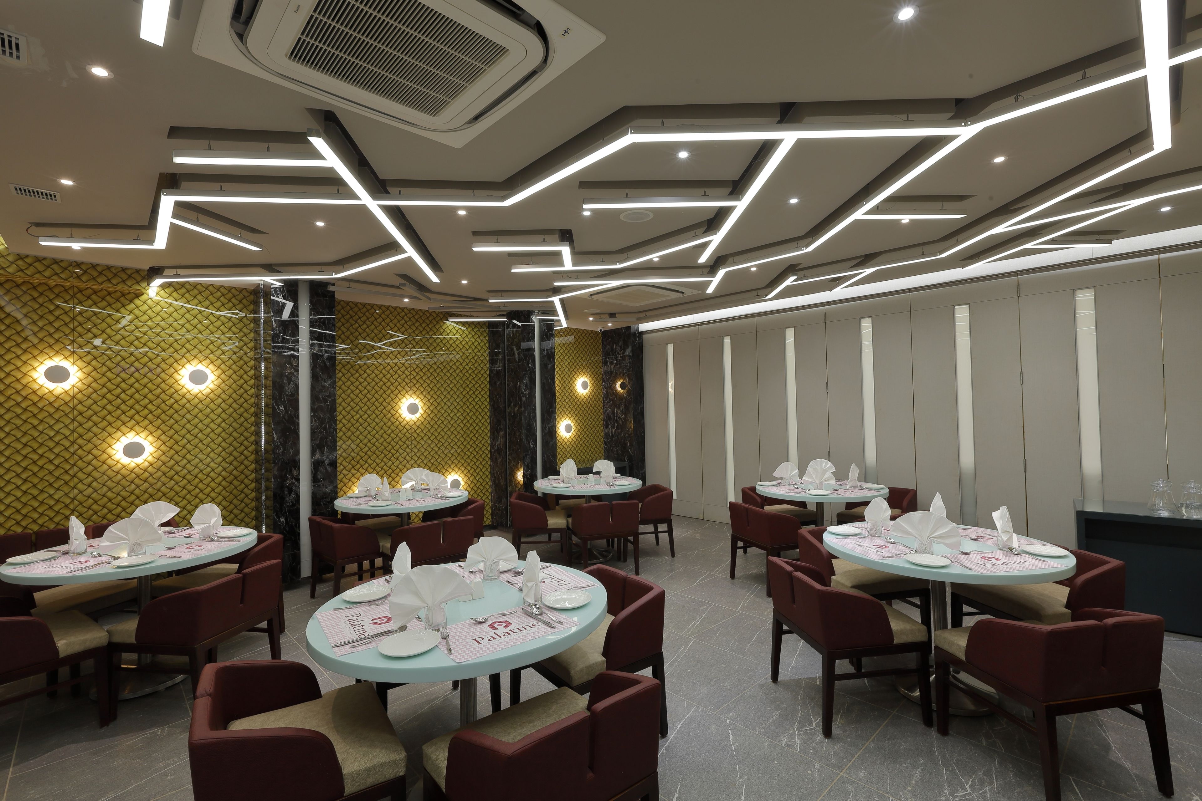 A restaurant with round tables, red chairs, and a modern ceiling design.