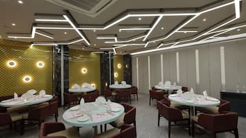A restaurant with round tables, red chairs, and a modern ceiling design.