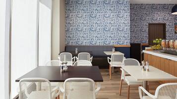 Een restaurant met witte stoelen en tafels, een behangetje en een presentatie van fruit.