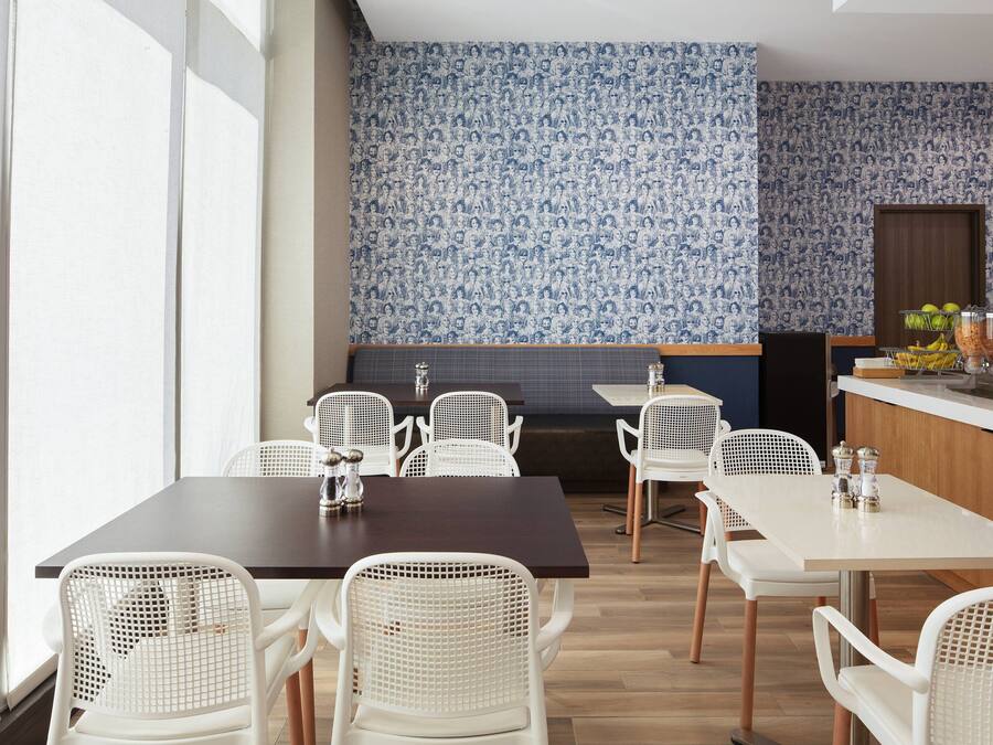 Een restaurant met witte stoelen en tafels, een behangetje en een presentatie van fruit.