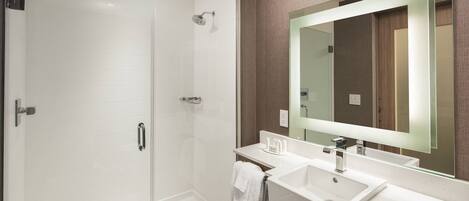 A modern bathroom with a glass-enclosed shower, two sinks, and a large mirror.