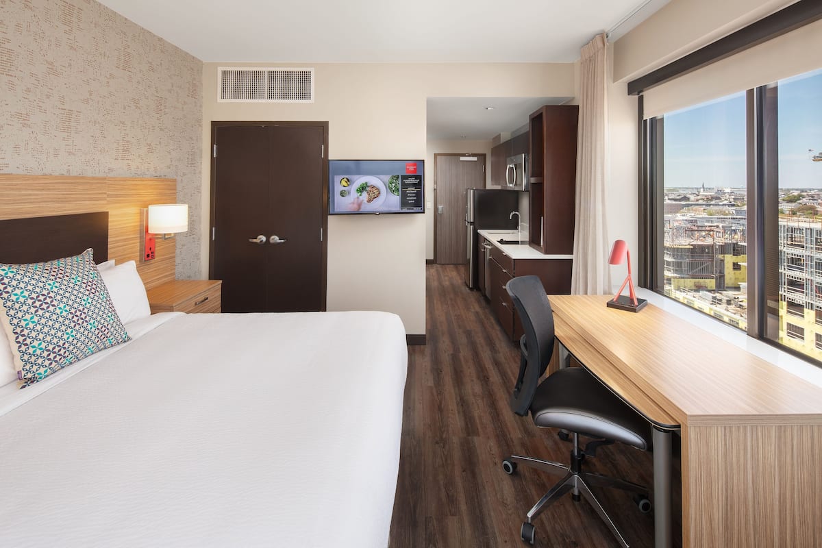 A hotel room with a bed, desk, and TV.
