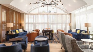 A modern hotel lobby with a central seating area, a dining table, and a large window with sheer curtains. - TownePlace Suites New Orleans Downtown/Canal Street (New Orleans)