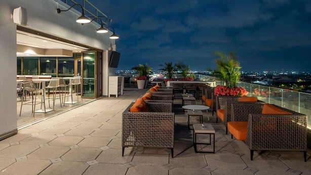 An outdoor terrace with wicker furniture, a glass railing, and a view of the city at night. - TownePlace Suites New Orleans Downtown/Canal Street (New Orleans)