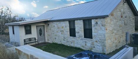 A stone building with a metal roof, a front door, and a small patio area.