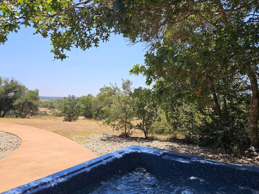 Un jacuzzi rodeado de árboles y un sendero de tierra.