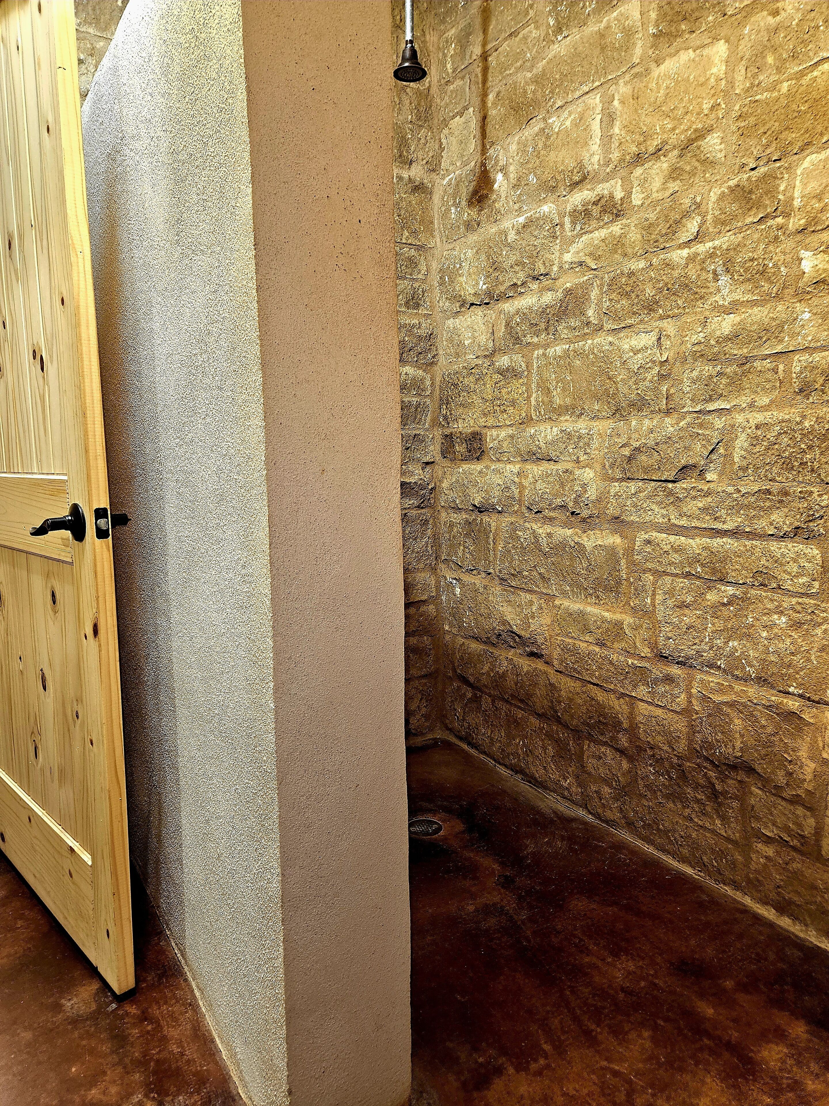 Ein Teil eines Raumes mit einer Holztür, einer strukturierten Wand und einer Steinwand.