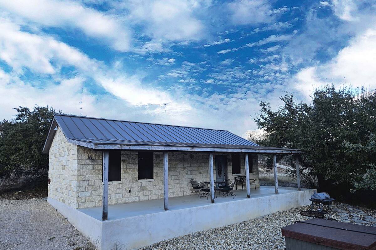 A stone building with a metal roof and a covered porch.