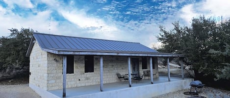 A stone building with a metal roof and a covered porch.