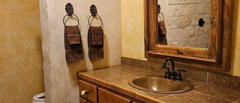 A bathroom with a wooden vanity, a sink, a mirror, and a toilet.