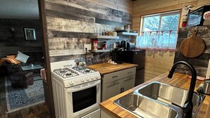 A compact kitchen with a gas stove, a sink, and wooden countertops. - Guest House Austria (Stewart)