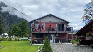 A two-story building with a balcony, a door, and a small garden area with a statue. - Guest House Austria (Stewart)