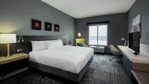 Una camera d'albergo moderna con un letto grande, una scrivania, una sedia e una finestra con vista sulla città.