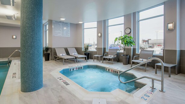 Area piscina con sedie a sdraio, un orologio e un cartello con le regole della spa.