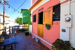 A colorful building with the number 1050, outdoor seating with chairs and tables, and potted plants. - Casa Santurce - Hostel (San Juan)
