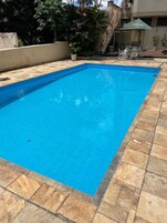 Una piscina al aire libre, sillones reclinables de piscina