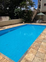 Una piscina al aire libre, sillones reclinables de piscina