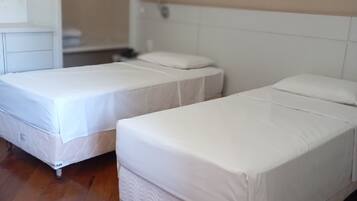 A room with two single beds, a wardrobe, and a wooden floor.