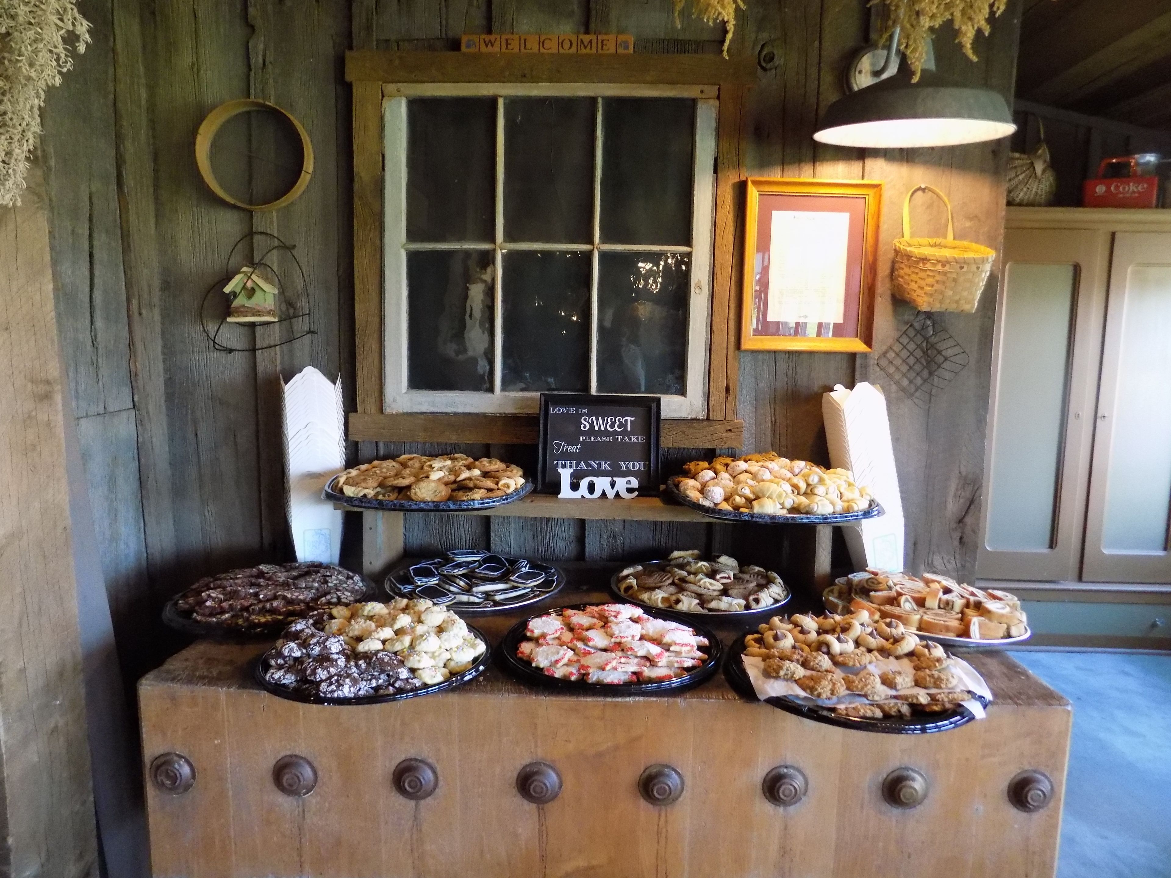 A wooden buffet table with various desserts and a sign that says "Love is a Sweet Treat Please Take Thank You Love".