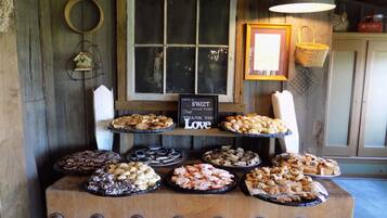 A wooden buffet table with various desserts and a sign that says "Love is a Sweet Treat Please Take Thank You Love".