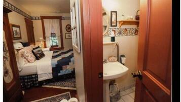 A bedroom with a bed, a nightstand, and a window with curtains.