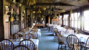 Un amplio comedor con mesas y sillas de madera, una zona de buffet central y decoraciones colgantes.