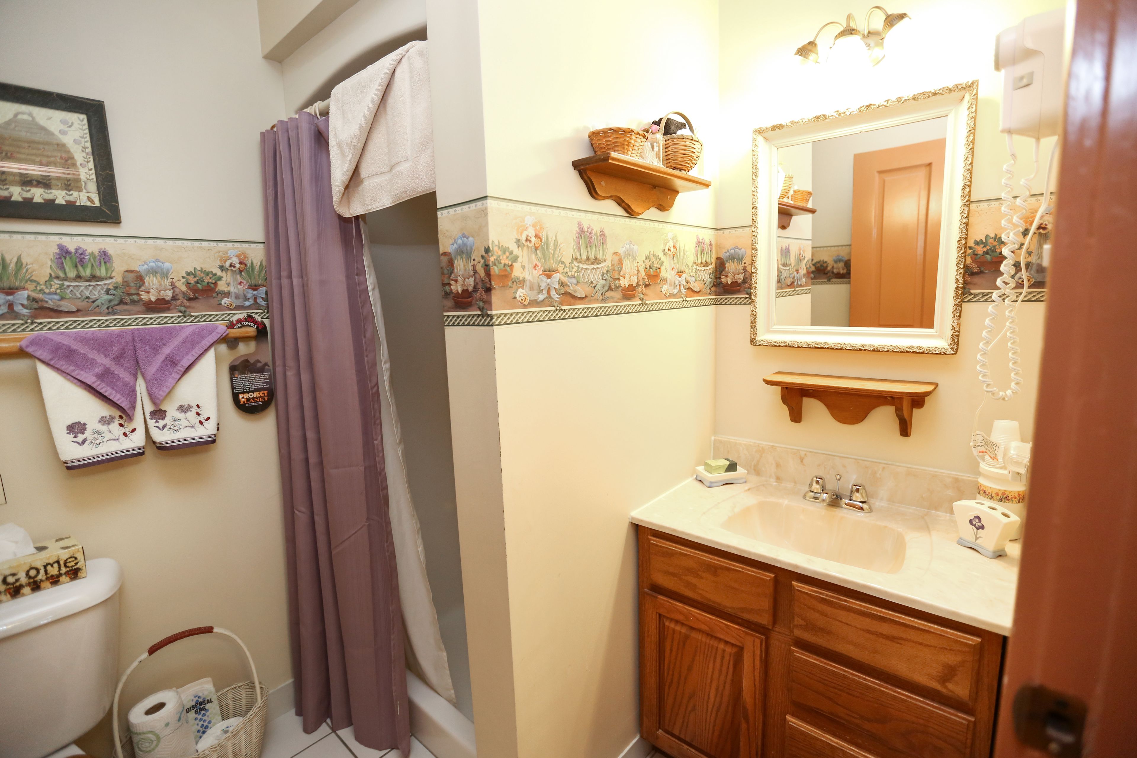 A bathroom with a shower curtain, a sink with a mirror, and a towel rack.