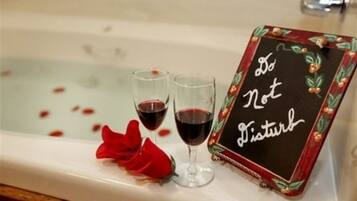A bathtub with two glasses of red wine and a sign that reads "Do Not Disturb".