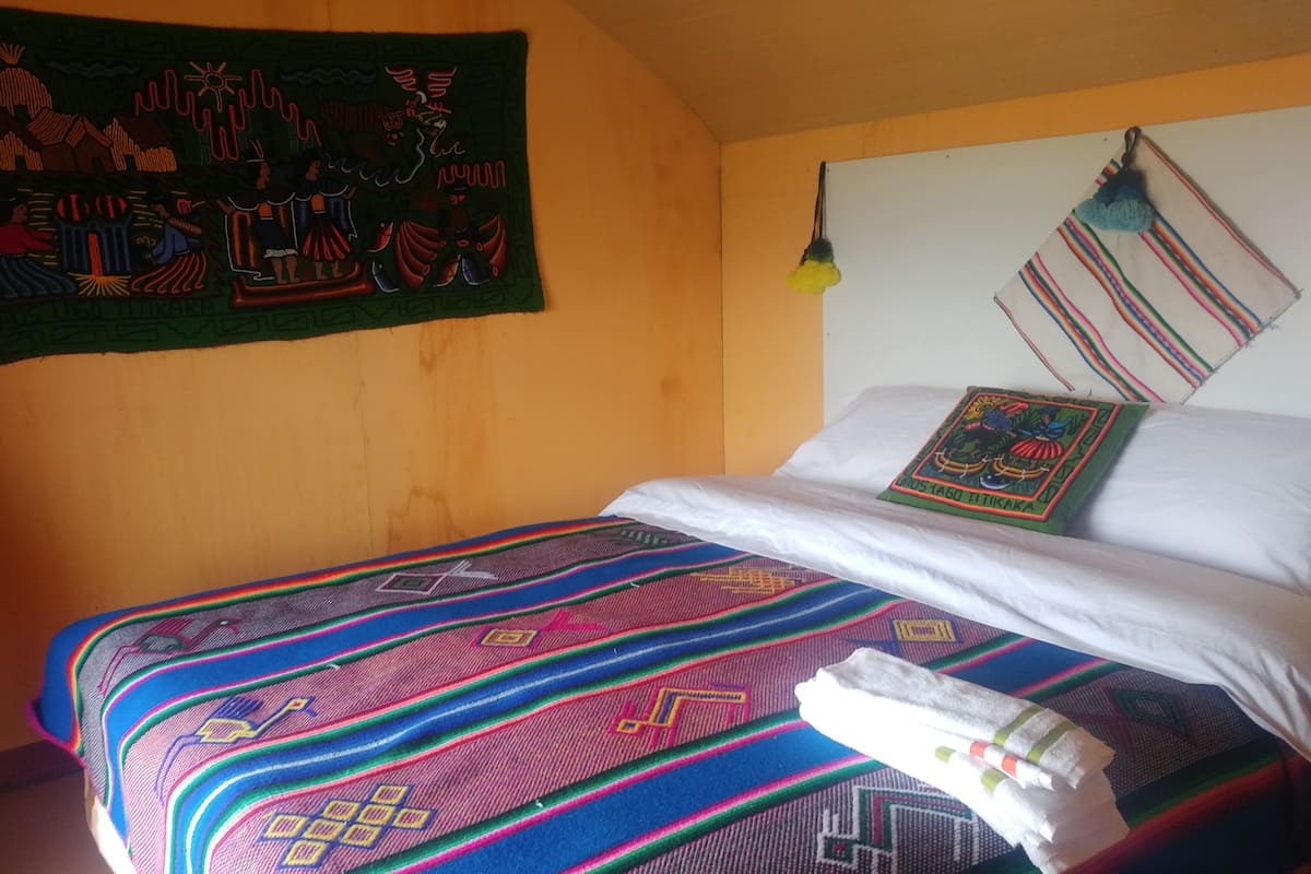 A bed with colorful bedding, a wall hanging, and a hanging towel.