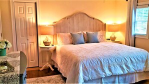 A bedroom with a large bed, two bedside tables with lamps, a dresser, and a door. - The Elmere House Bed & Breakfast (Wells)