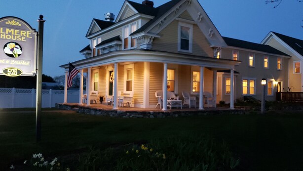 A large two-story house with a porch, a sign for Elmere House Bed & Breakfast, and an American flag. - The Elmere House Bed & Breakfast (Wells)