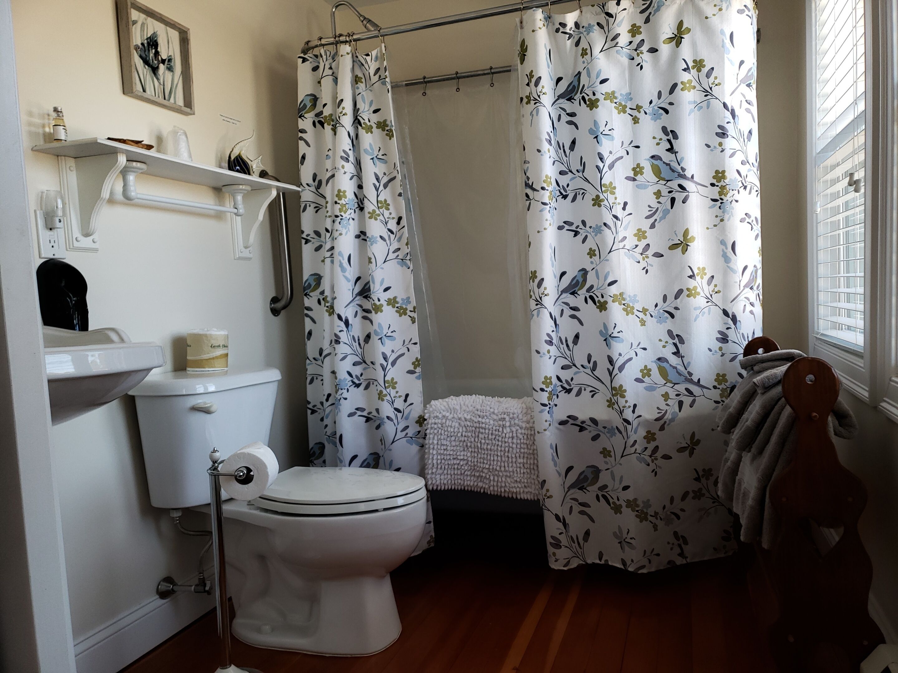 Un baño con inodoro, lavamanos y cortina de ducha con estampado floral.