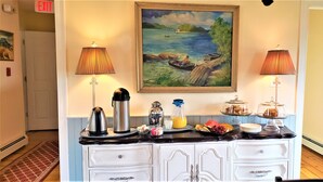 A breakfast bar with a painting, lamps, and a fruit display. - The Elmere House Bed & Breakfast (Wells)