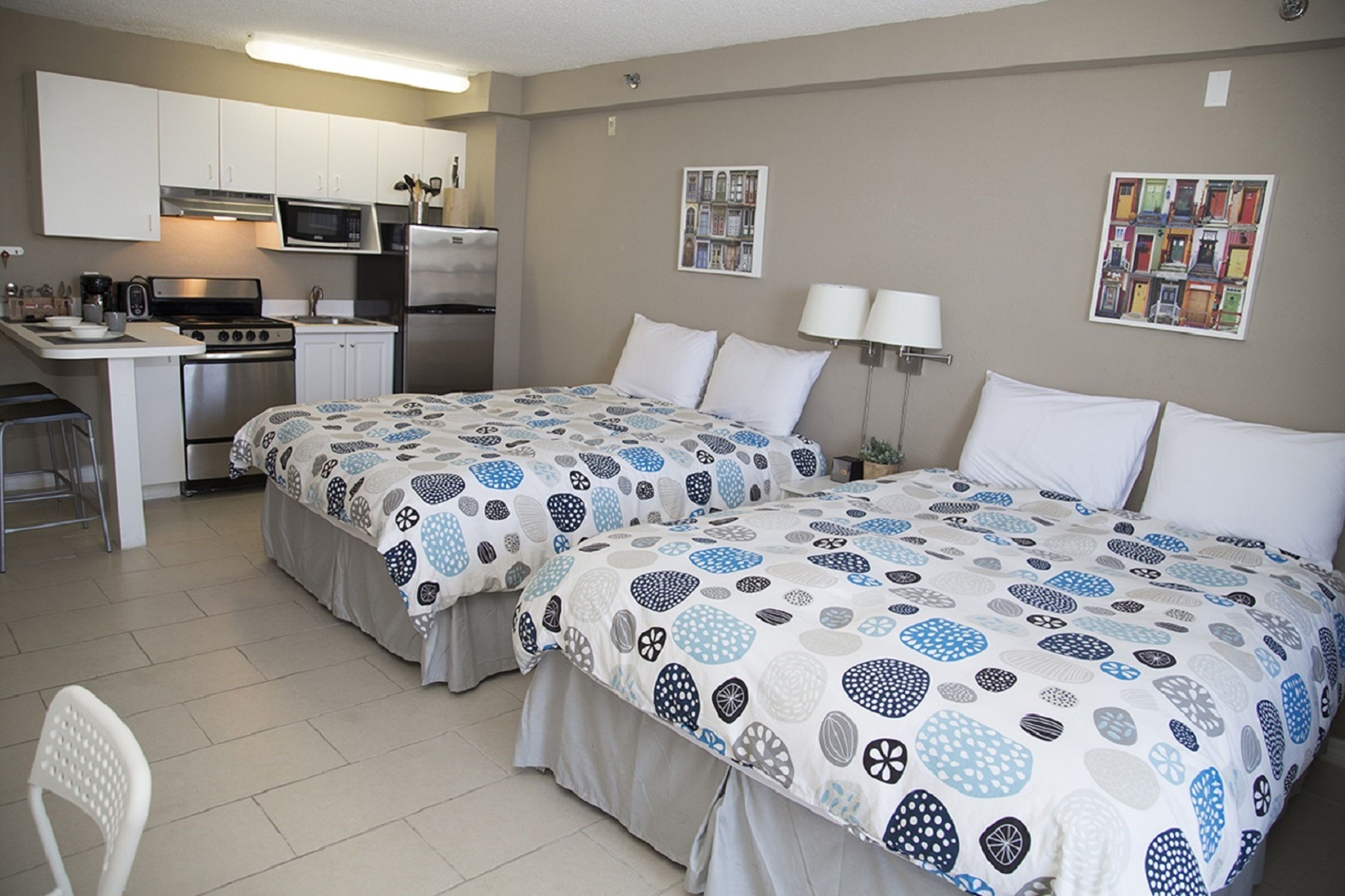 Habitación de hotel con dos camas, kitchenette y zona de comedor.