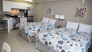 A hotel room with two beds, a kitchenette, and a dining area.