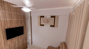 A room with a wooden panel wall, a ceiling fan, a mounted flat-screen TV, and a framed artwork on the wall. - Lacqua Di Roma - JC Temporada (Caldas Novas)