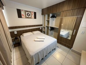 A hotel room with a bed, a bedside table, a mirror, a wardrobe, and a wall art piece. - Lacqua Di Roma - JC Temporada (Caldas Novas)