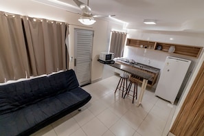Cozinha compacta com micro-ondas, geladeira e banquetas de bar.