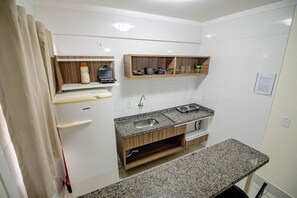 A compact kitchen with a built-in sink, wooden shelves, and a granite countertop. - Lacqua Di Roma - JC Temporada (Caldas Novas)
