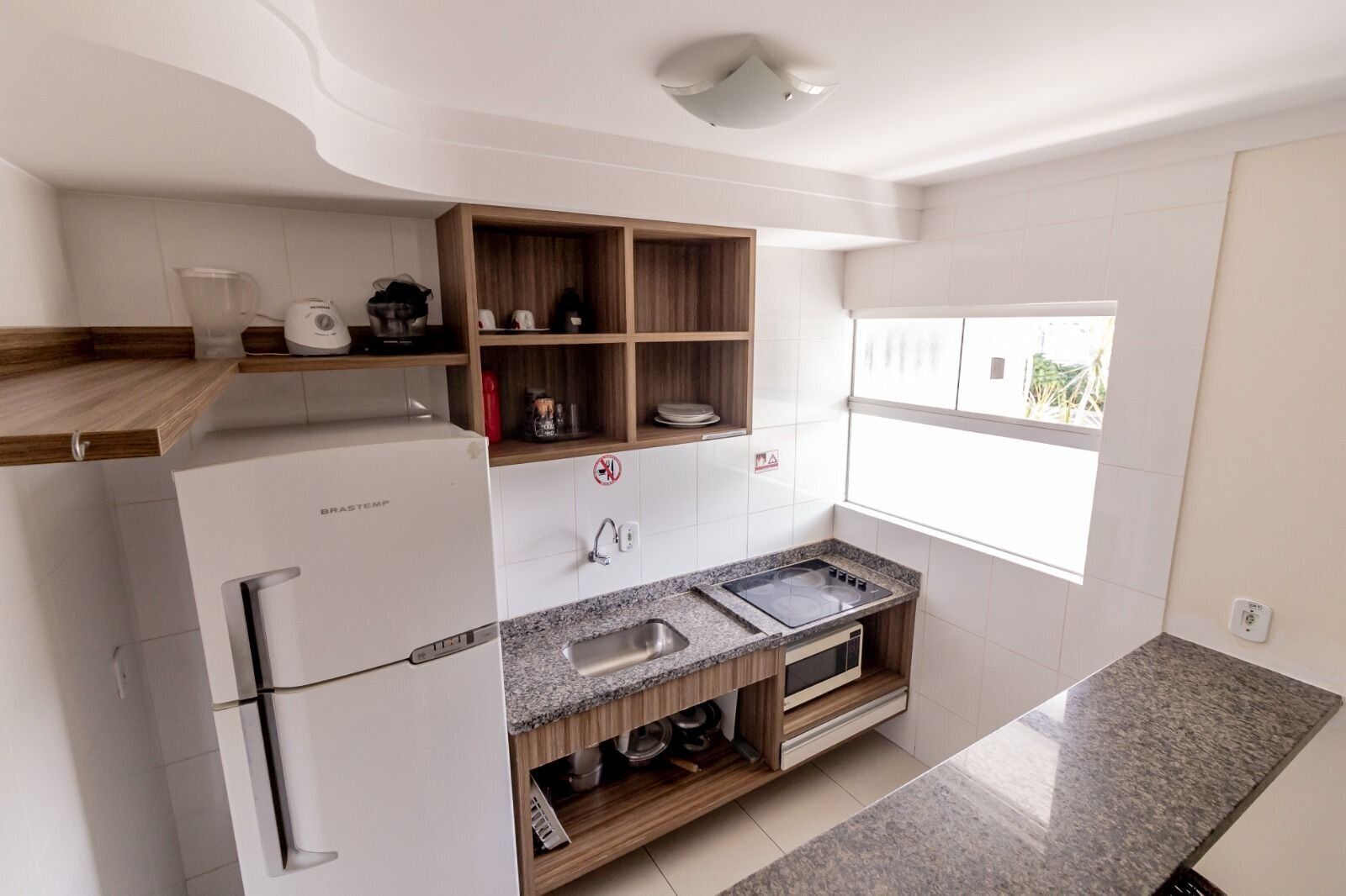 A compact kitchen with white cabinetry, a built-in stove, and a window providing natural light.